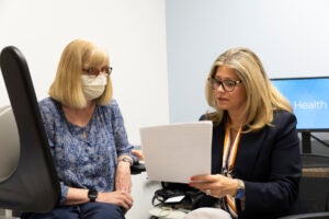 Two women in a medical office look at a piece of paper.