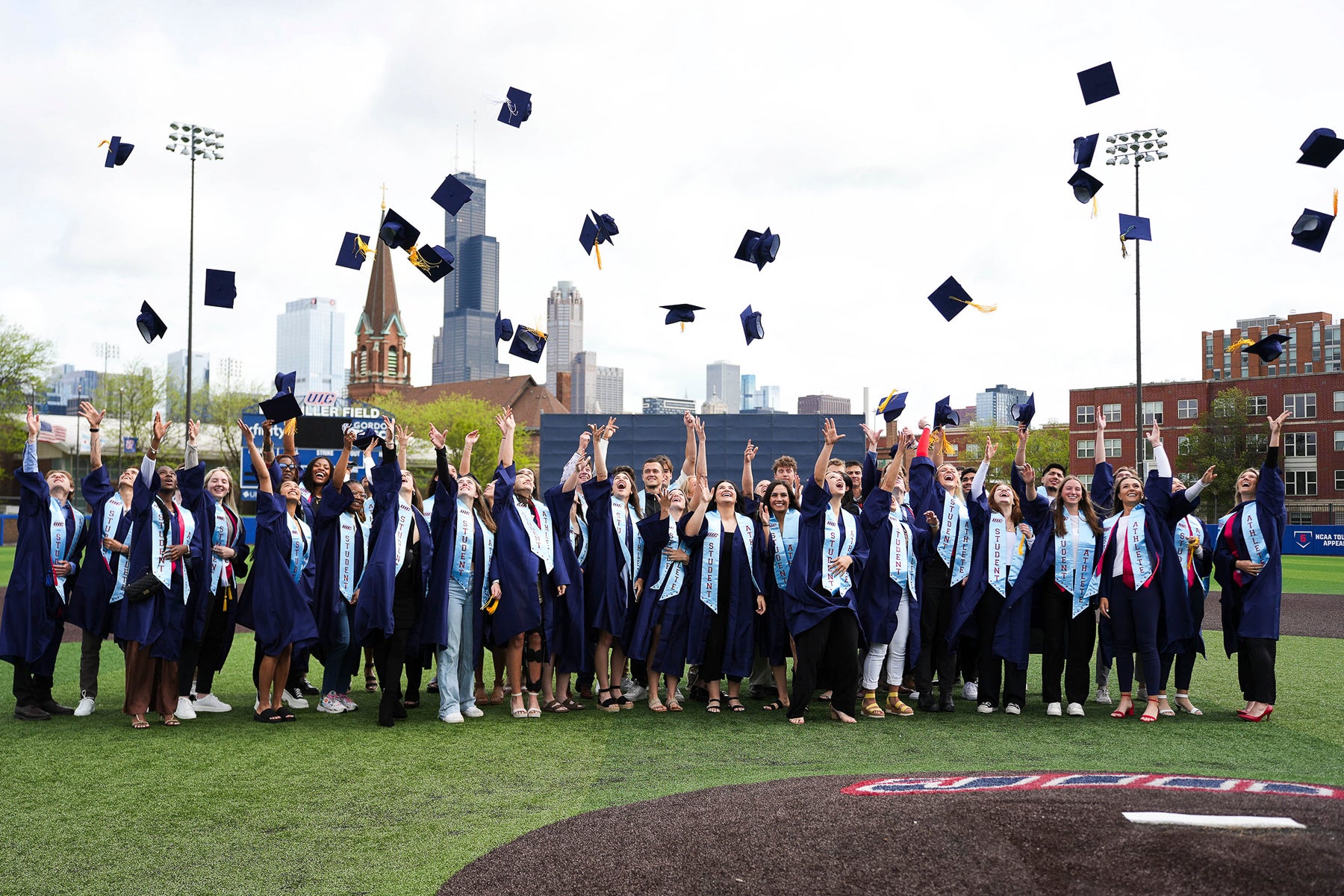 Student-athletes from the 2024 graduating class throw their caps in the air at their graduation.