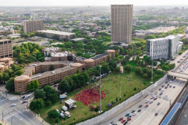 Aerial view of the University of Illinois Chicago campus, showcasing a large gathering of people in red shirts on a field near campus.