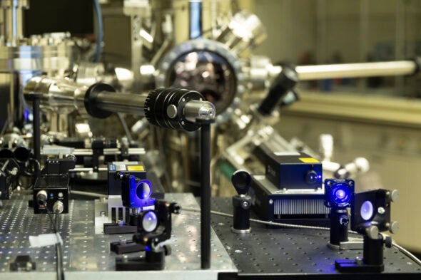 Chrome and black tubing on scientific equipment with blue lasers in the foreground.