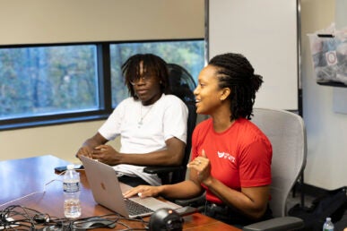 Jeniece Fleming coordinator of Brothers Teaching sits with student Gaius Anighoro.