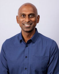 Headshot of a man in a blue collared shirt.