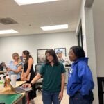 Two women look at a laptop in a classroom.