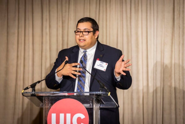 A man in a suit and glasses speaks at a podium