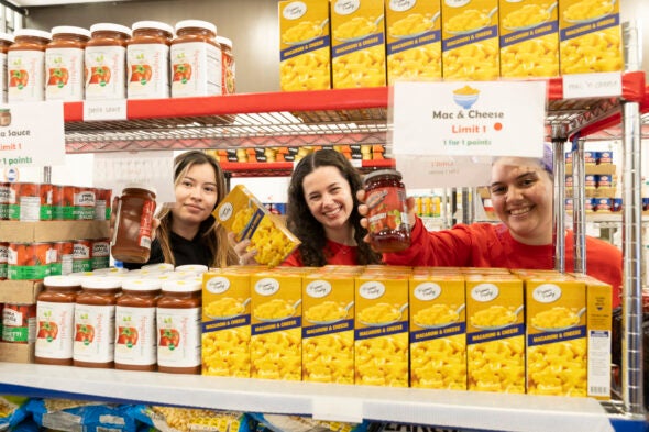 UIC Pop-Up Pantry staff pose behind food on shelves.