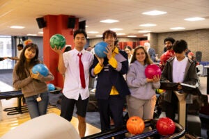 Students hold up bowling balls at Millennium Lanes