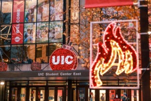 Photo of UIC Student Center East with a UIC circle logo decorated with holiday lights