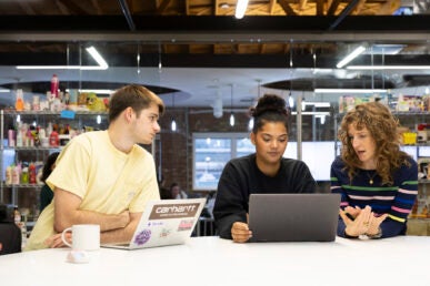 Three people working together looking at a computer