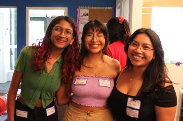 three women wearing name tags smile for a photo