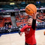 A man in a red t-shirt goes for a layup basketball shot at Credit Union 1 Arena